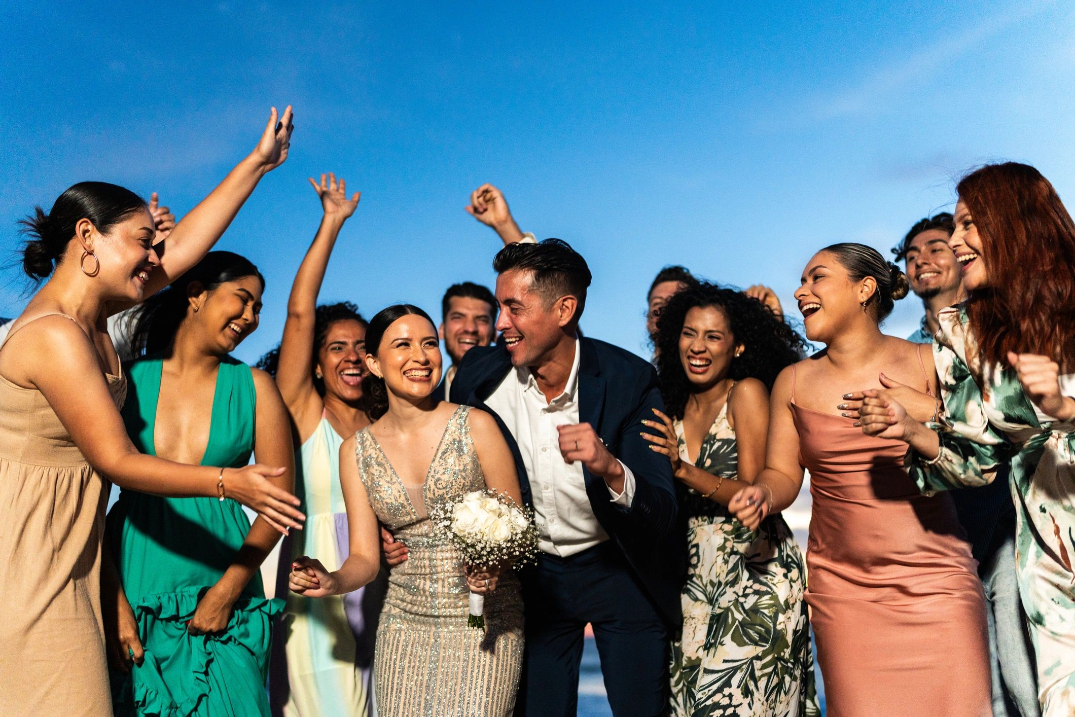 Bride and groom celebrating with wedding guests on the beach